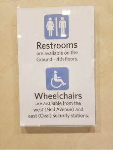Sign indicating where the restrooms are located as well as where to obtain a wheelchair.